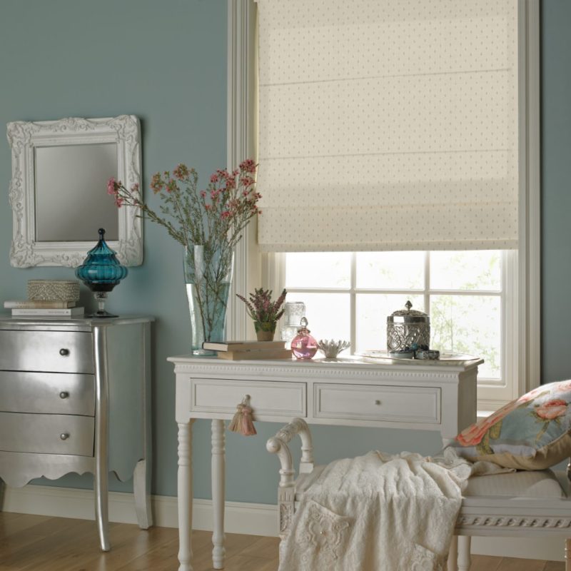 A stylish bedroom with a large window with a cream roman blind