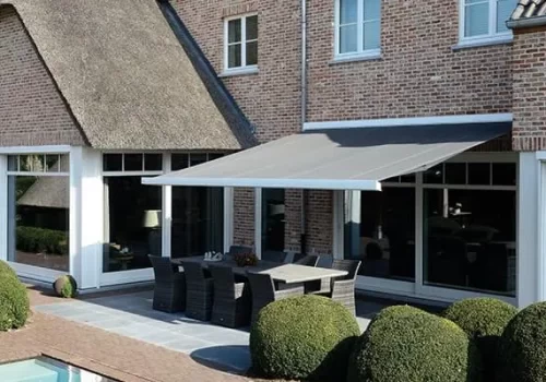 A grey retractable awning over an outdoor patio dining area